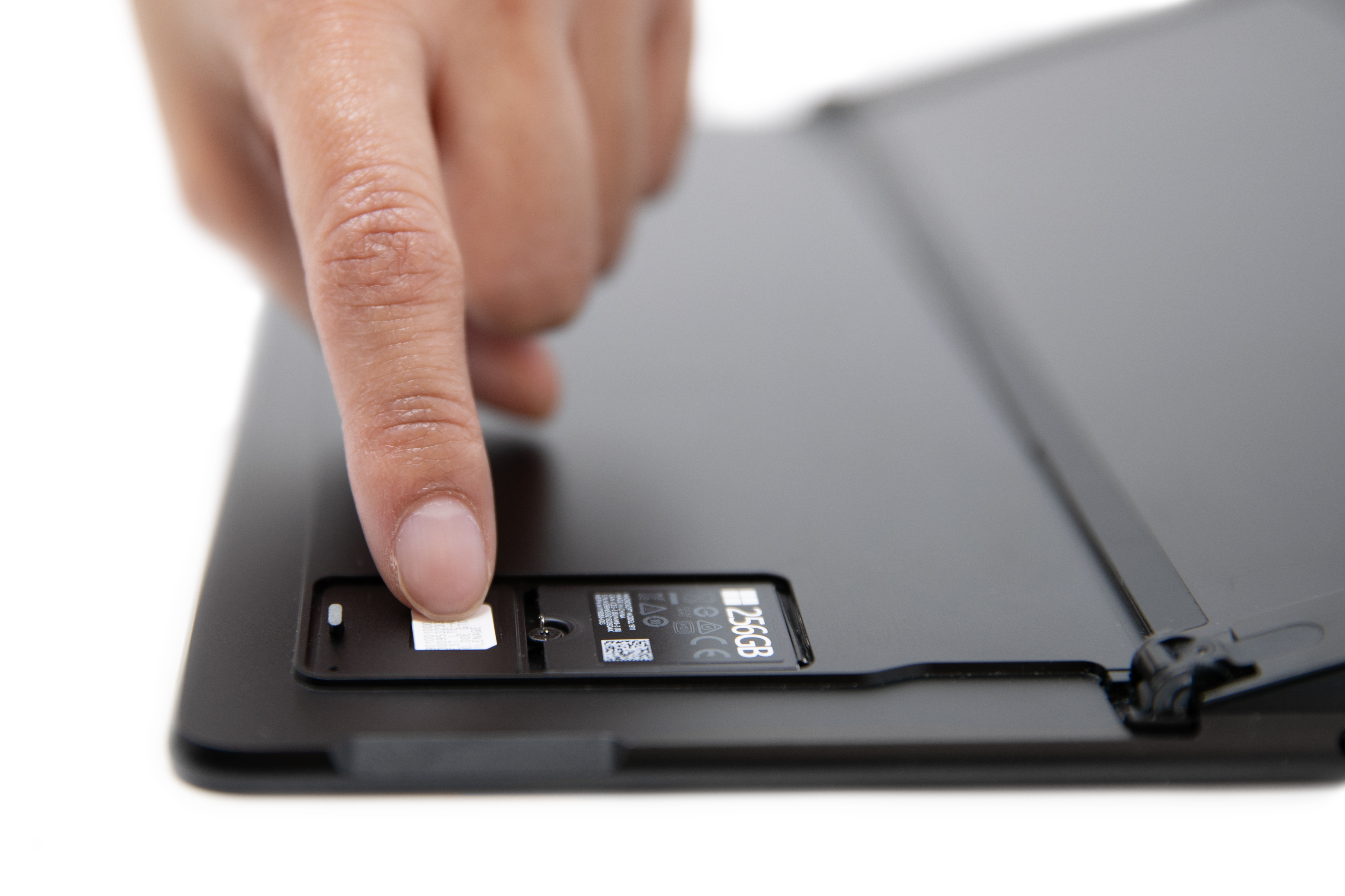 A person sliding in a SIM card into the Surface Pro X SIM slot.